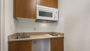 A compact kitchen with a built-in microwave, a sink, and a stovetop.