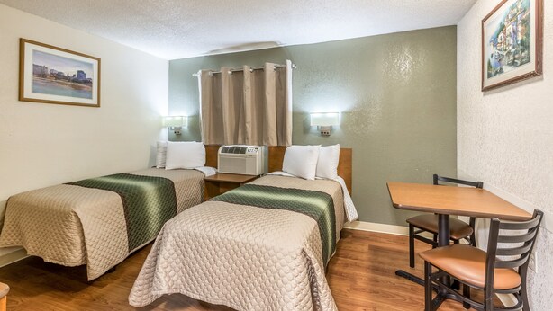 Een hotelkamer met twee bedden, een houten tafel en een stoel.