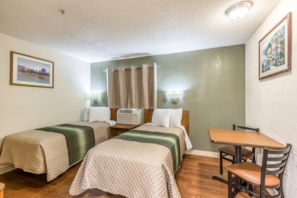 A hotel room with two beds, a wooden table, and a chair.