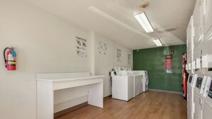 A laundry room with a white desk, washing machines, and a fire extinguisher.