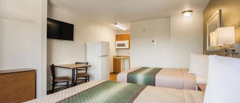 Una habitación de hotel con cama, escritorio, silla, televisor, microondas y armario.