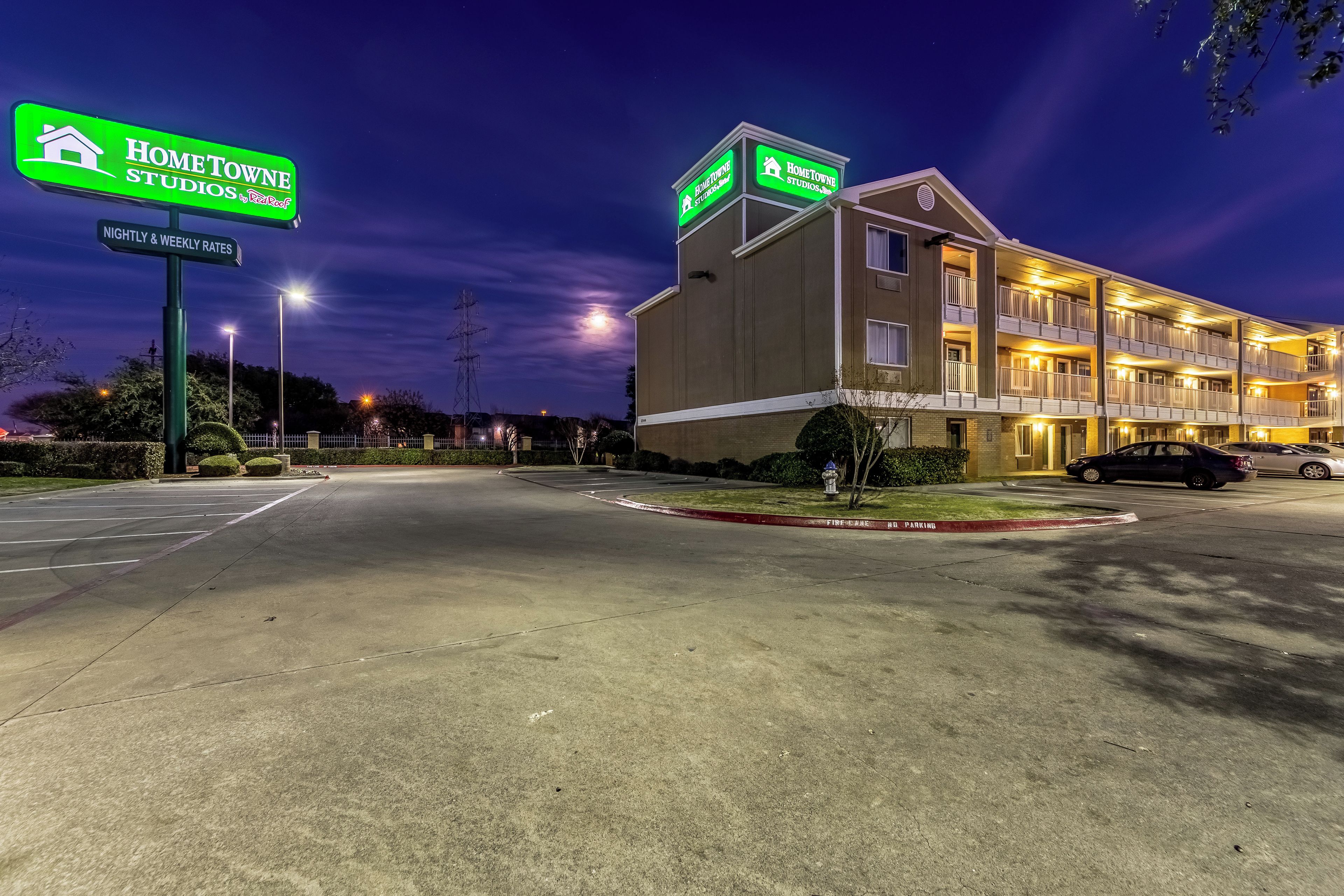 A hotel with a sign indicating 'HOMETOWNE STUDIOS' and 'NIGHTLY & WEEKLY RATES'.