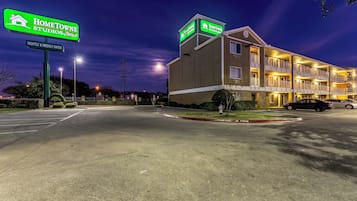 Un hôtel avec une enseigne indiquant « HOMETOWNE STUDIOS » et « TARIFS JOURNALIERS ET HEBDOMADAIRES ».