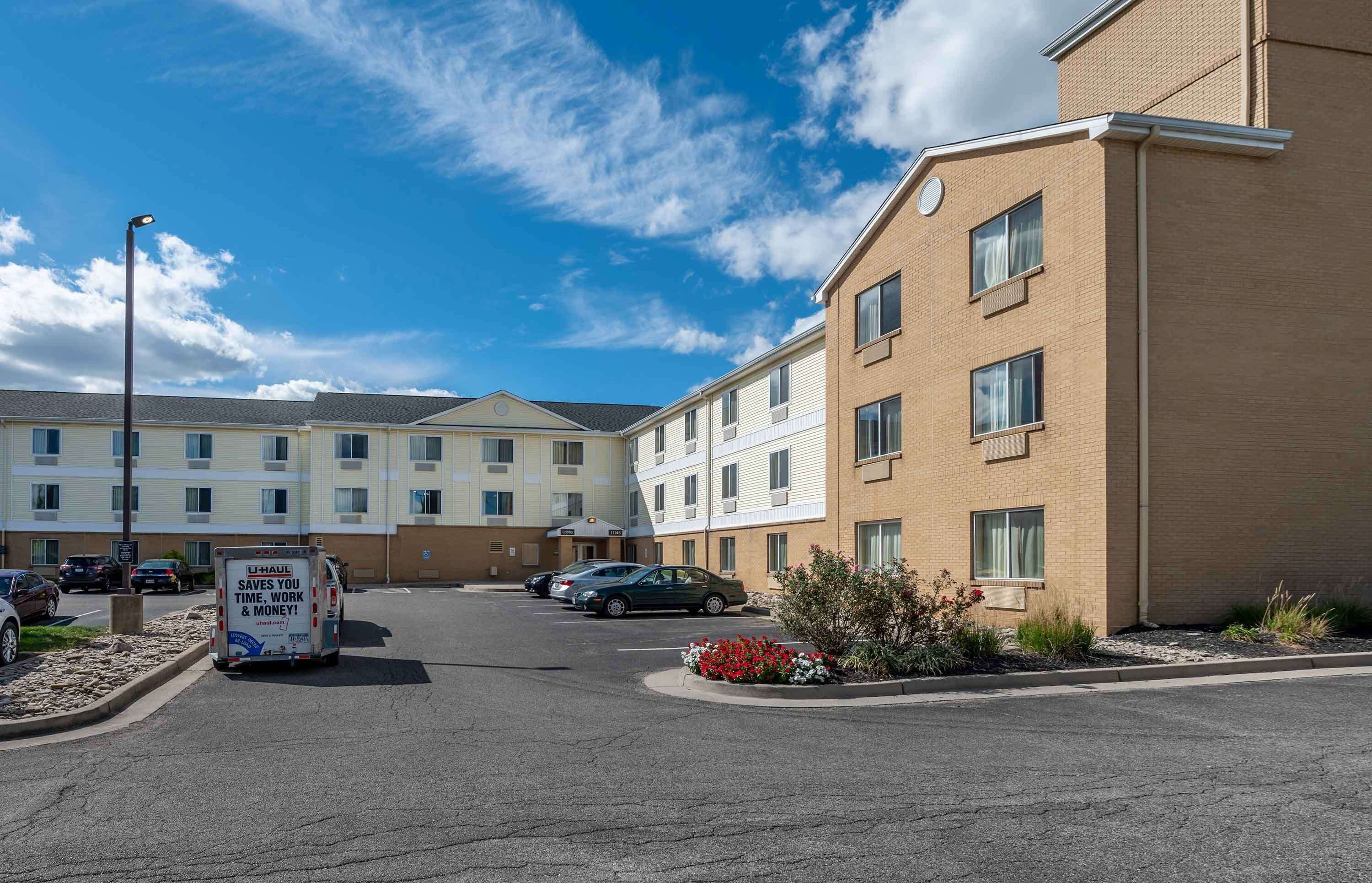 A hotel with a parking lot, a moving truck, and a clear blue sky.