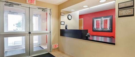 Ein Empfangsbereich mit roter Wand, einer Uhr und einer Rezeption.