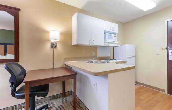 A compact kitchenette with a microwave, refrigerator, and a small dining area with a chair and table. - Extended Stay America Suites Washington DC Gaithersburg N (Gaithersburg)