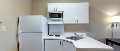 A compact kitchenette with a built-in microwave, a refrigerator, a sink, and a stove.