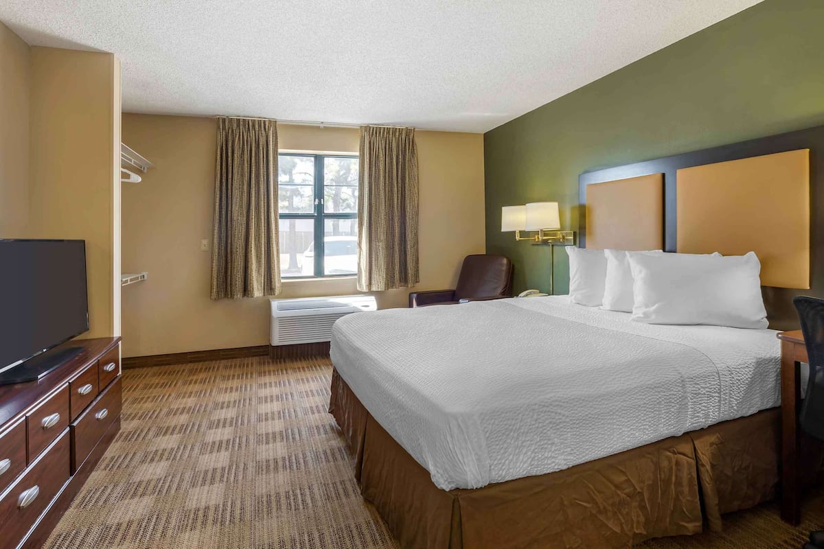Habitación de hotel con una cama grande, televisión, escritorio y una silla.