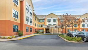 A multi-story hotel with a lobby entrance, parking area, and a row of parked cars. - Extended Stay America Select Philadelphia Malvern Great Vall (Malvern)