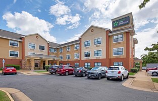 A hotel with a sign reading "Extended Stay America" and a parking lot with several cars.