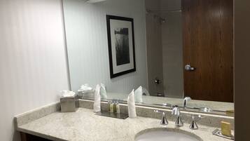 Une salle de bain avec un grand miroir, deux lavabos, un porte-serviettes et un tableau encadré au mur.