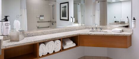 Une salle de bain moderne avec un grand miroir, un lavabo et un espace douche.