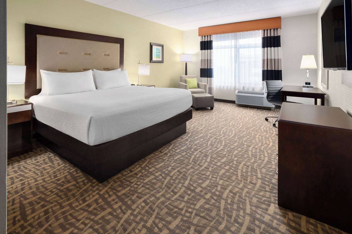 Une chambre d’hôtel avec un grand lit, un bureau, une chaise et un téléviseur.