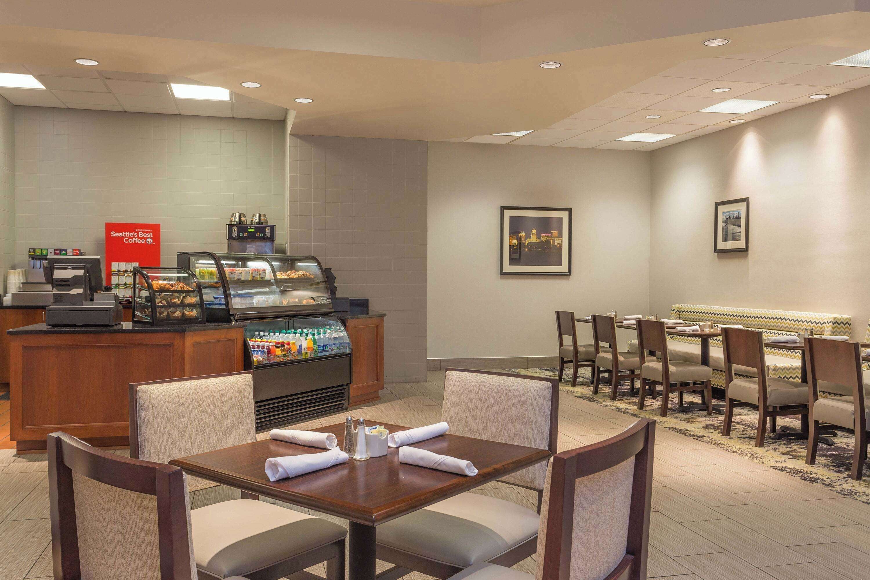 Un hall d’hôtel avec un coin café, un espace salon et un tableau encadré au mur.