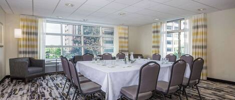 A conference room with a round table, chairs, and a carpeted floor.