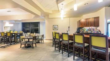Un vestíbulo de hotel con una zona de bar, mesas y sillas para comer.