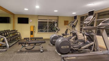 A gym with treadmills, elliptical machines, and dumbbells.