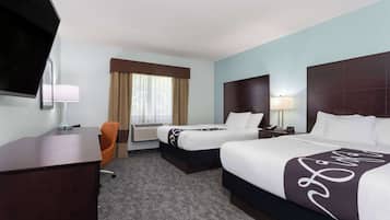 Une chambre d’hôtel avec deux lits, un bureau, une télévision et une fenêtre avec des rideaux.