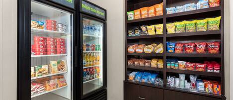 A self-service snack and beverage area with refrigerated drinks and a variety of snacks.
