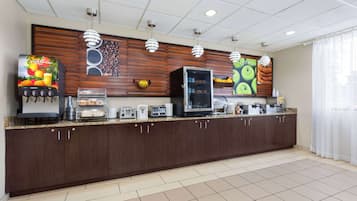 A modern hotel kitchen with a long counter, equipped with a coffee machine, toaster, and refrigerator.