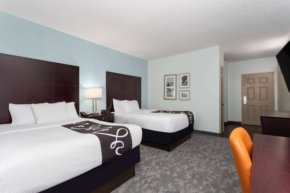 Ein Hotelzimmer mit zwei Betten, einem Schreibtisch und einem Stuhl.