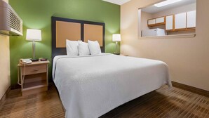 Habitación de hotel con cama, lámparas de noche, mesita de noche y un pequeño ventanal.