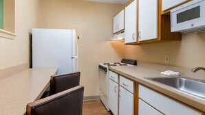 Una cocina compacta con armarios blancos, estufa, microondas y lavaplatos.