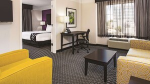 A hotel room with a bed, a desk, a chair, a sofa, and a television.