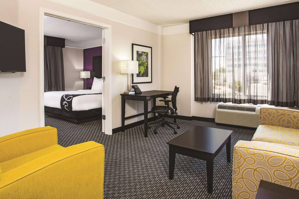 Una habitación de hotel con cama, escritorio, sillón, sofá y televisor.