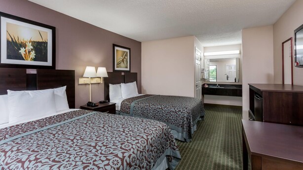 A hotel room with two beds, a desk, a mirror, and a bathroom visible in the background. - Days Inn by Wyndham Lugoff (Lugoff)