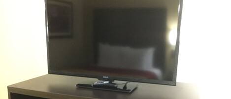 A flat-screen TV on a wooden stand.