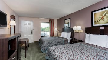 A hotel room with two beds, a desk, a TV, a door, and a window with a view.