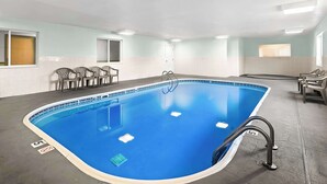 An indoor swimming pool with a blue interior, surrounded by chairs and a tiled floor. - SureStay Plus Hotel by Best Western Bettendorf (Bettendorf)
