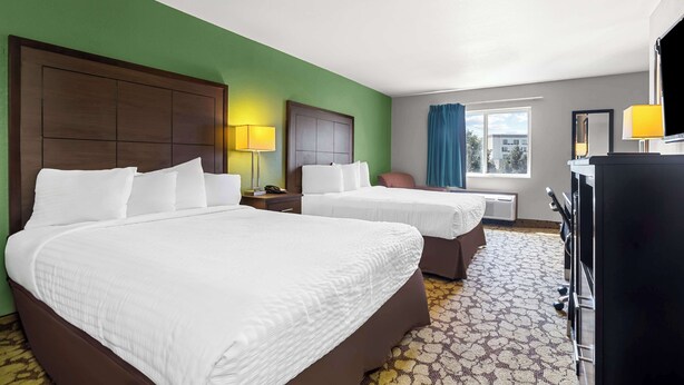 A hotel room with two beds, a desk, a chair, a TV, and a window with curtains. - SureStay Plus Hotel by Best Western Bettendorf (Bettendorf)