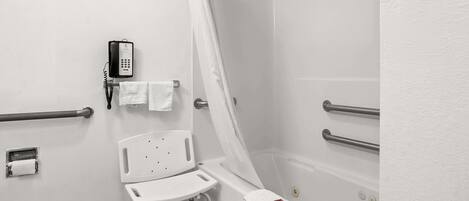 Un baño con una bañera blanca, una cortina de ducha, una silla blanca, un teléfono y un perchero.