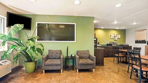 A reception area with two armchairs, a potted plant, a flat-screen TV, and a tiled floor. - SureStay Plus Hotel by Best Western Bettendorf (Bettendorf)