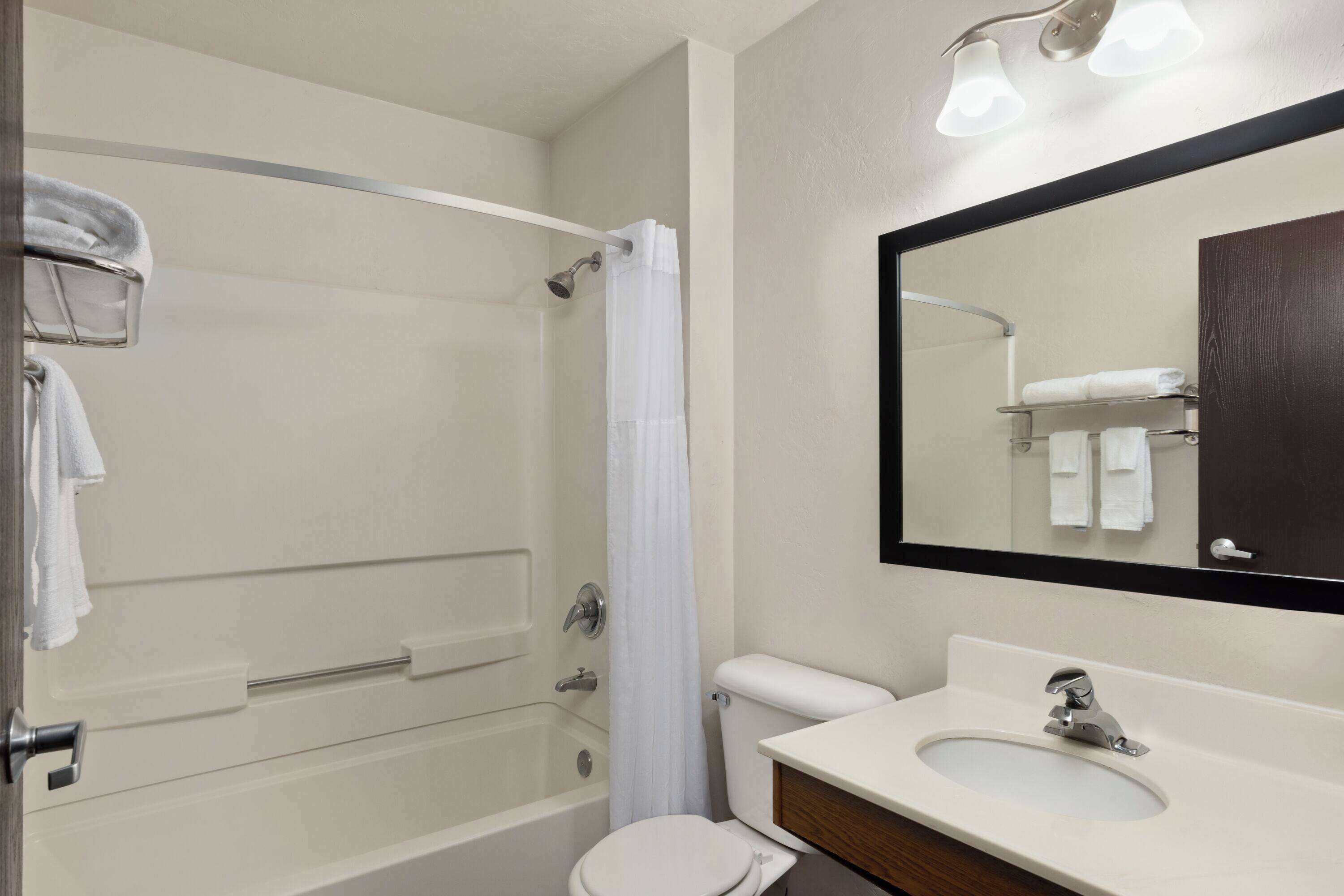A bathroom with a bathtub, toilet, sink, and a mirror.