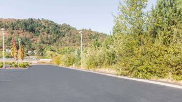 A parking lot with a road leading to a building, surrounded by trees and hills.