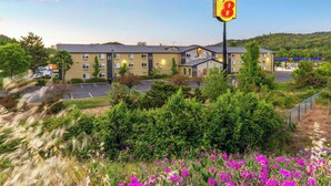 Ein Super 8 Hotel mit Parkplatz, umgeben von Grünflächen und blauem Himmel.