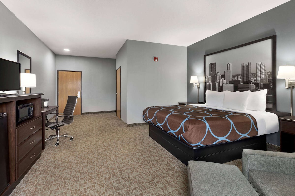 A hotel room with a bed, a desk with a computer, a chair, and a television.