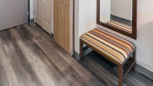 A hallway with a wooden bench, a mirror, and a door. - Townhome Inn And Suites (Cordova)