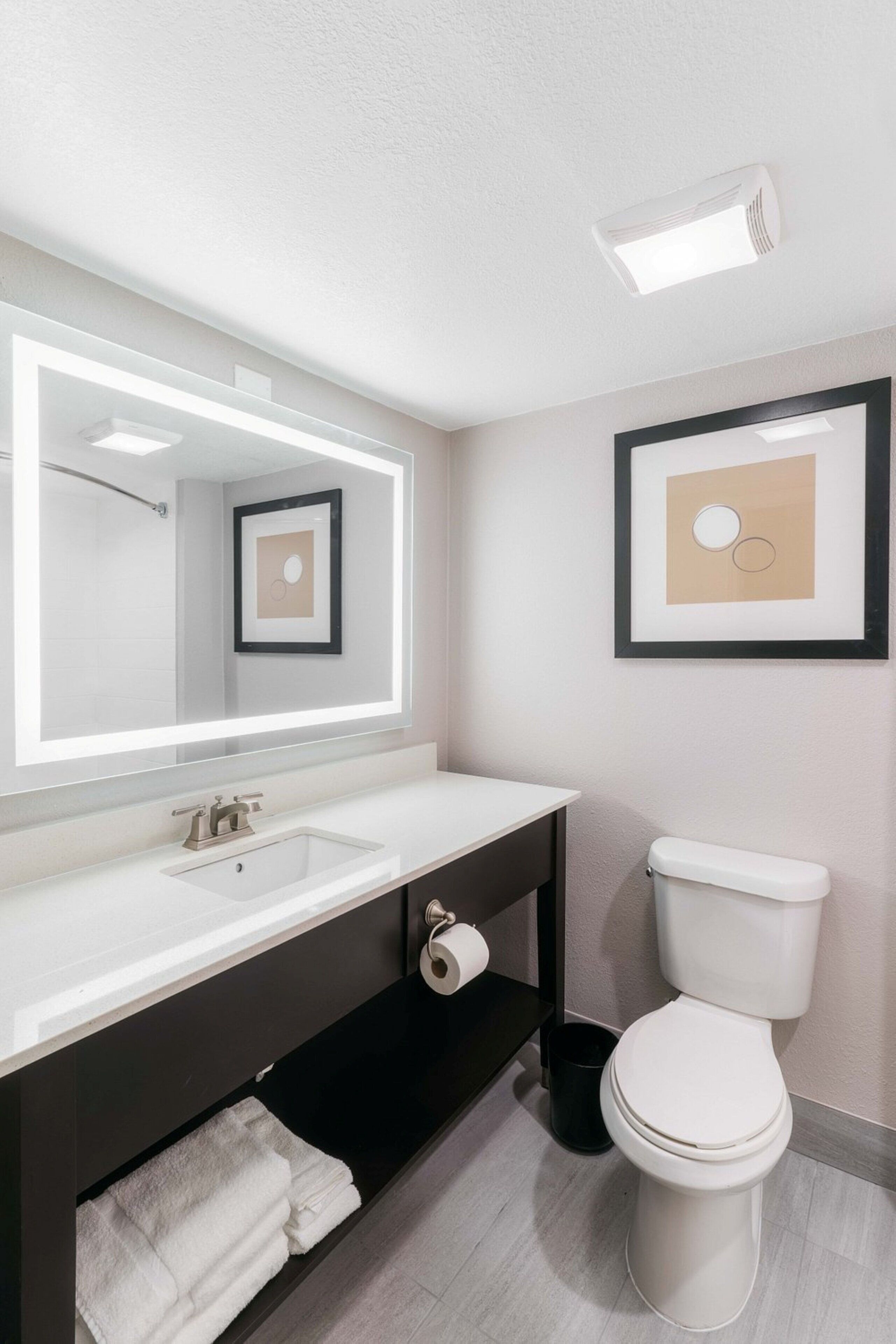 A modern bathroom with a white sink, mirror, and toilet.