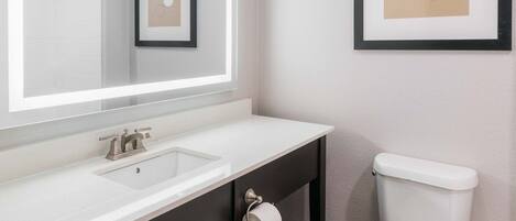 A modern bathroom with a white sink, mirror, and toilet.