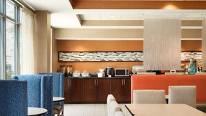 A hotel lobby with seating areas, a counter with a coffee machine, and a decorative wall. - Townhome Inn And Suites (Cordova)