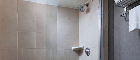 A bathroom with a glass-enclosed shower, a toilet, and a towel rack.