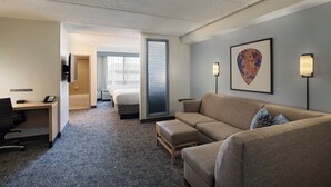 Une chambre d’hôtel avec un canapé, un bureau, un lit et une grande fenêtre.