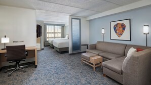 Une chambre d’hôtel comprenant un lit, un bureau, une chaise, un canapé, une petite table et un tableau encadré accroché au mur.
