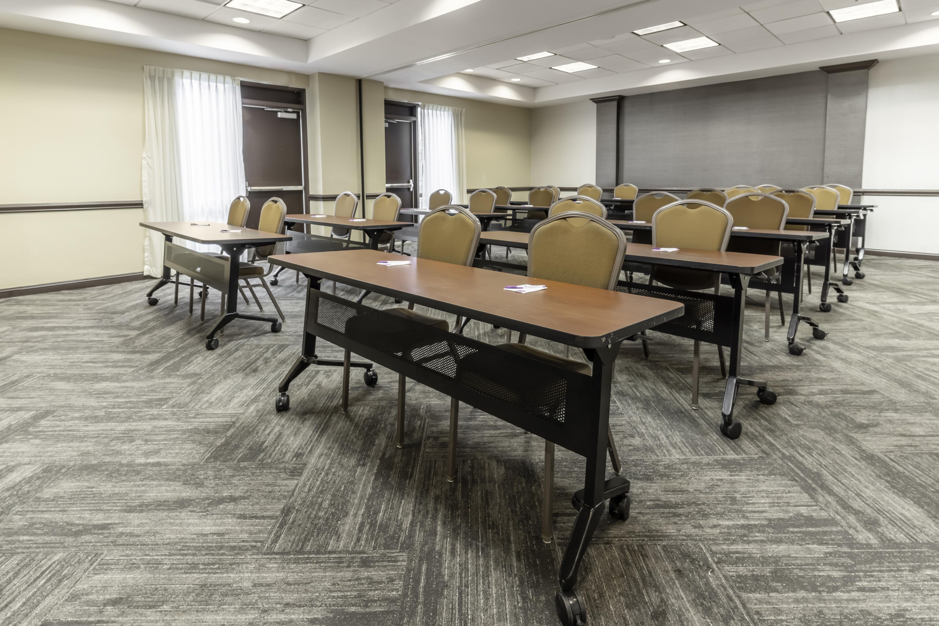 A conference room with multiple tables and chairs, a projector screen, and a whiteboard.