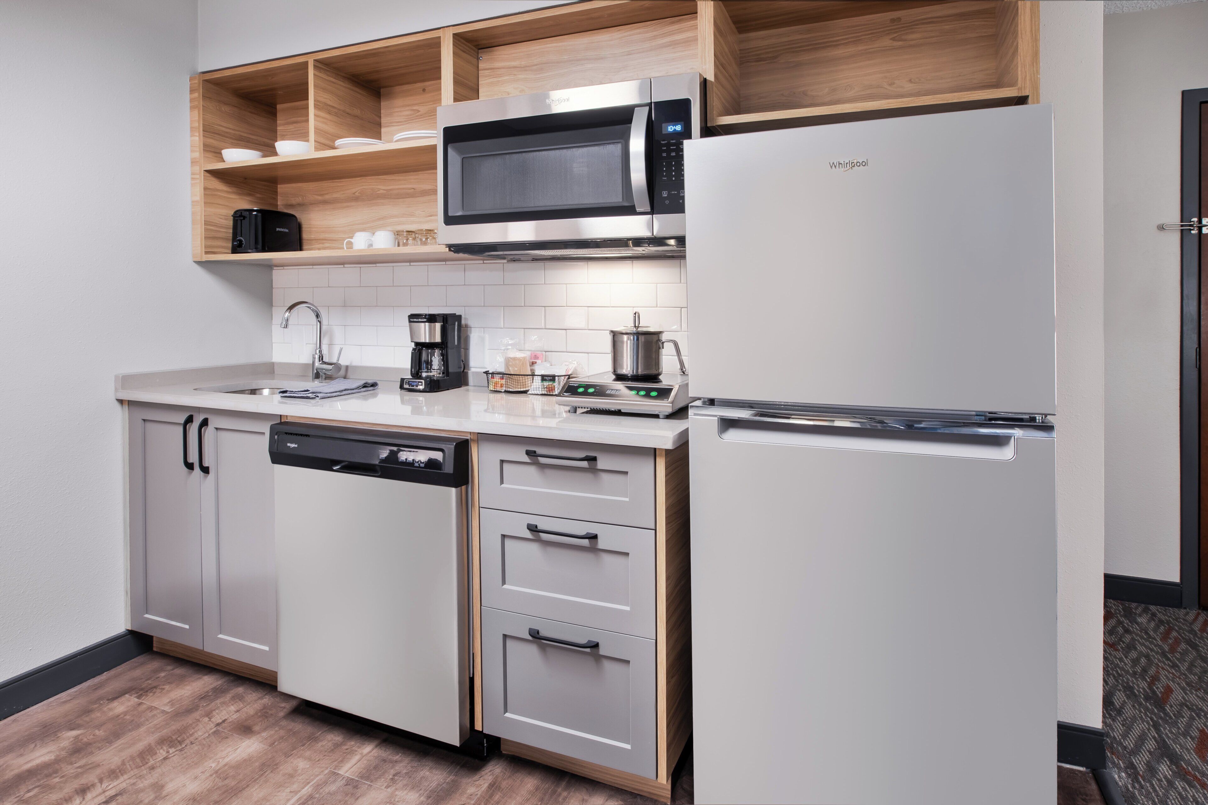A compact kitchenette with a microwave, coffee maker, and a built-in dishwasher.