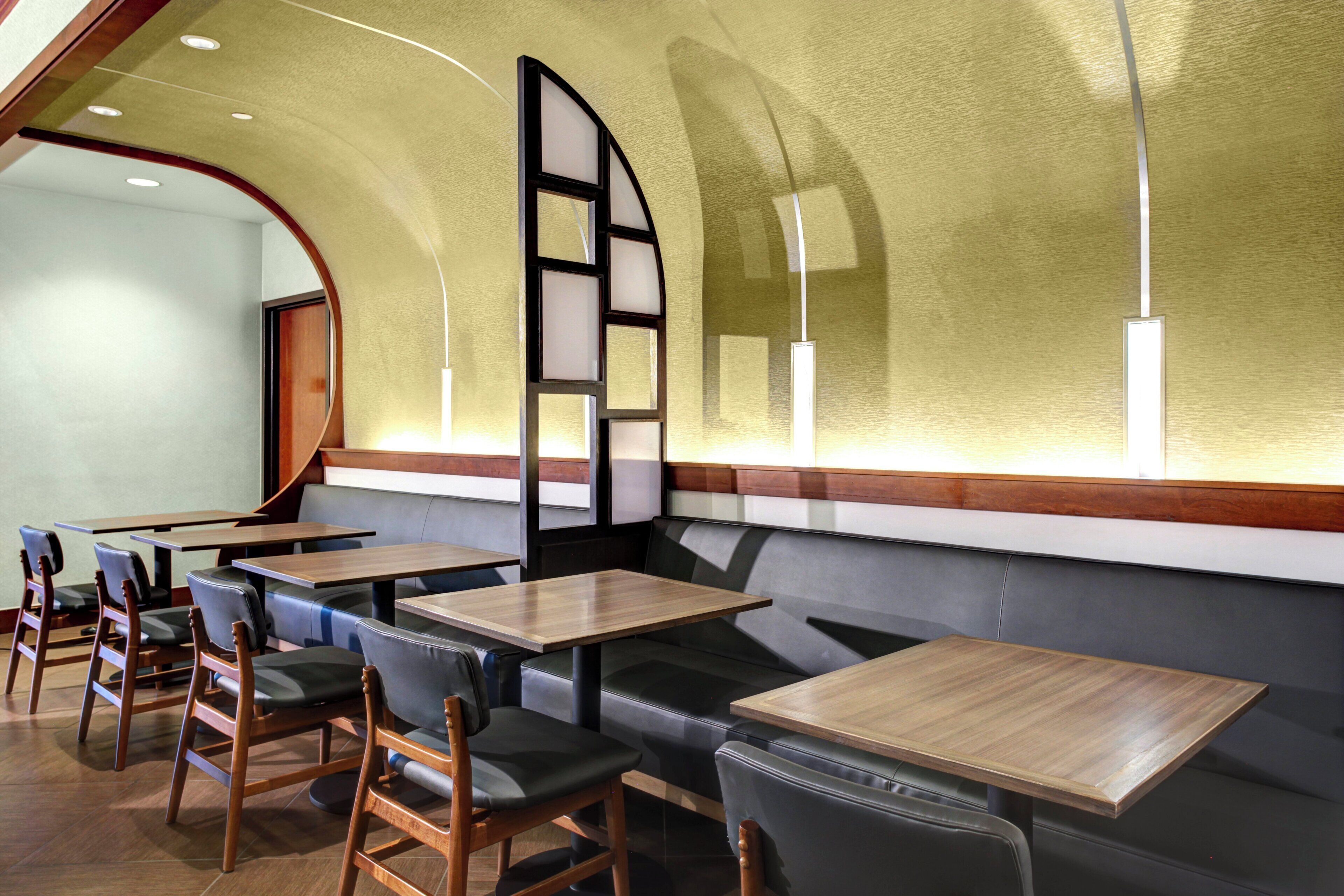 A restaurant interior with wooden tables, cushioned seating, and a curved ceiling.